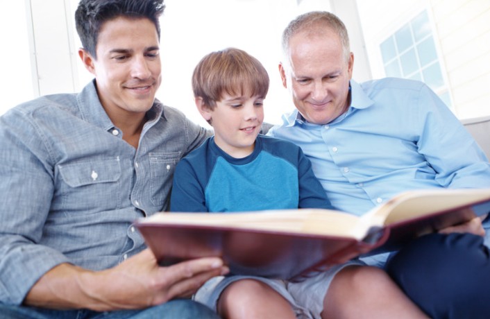 Family reading a book together on sofa.