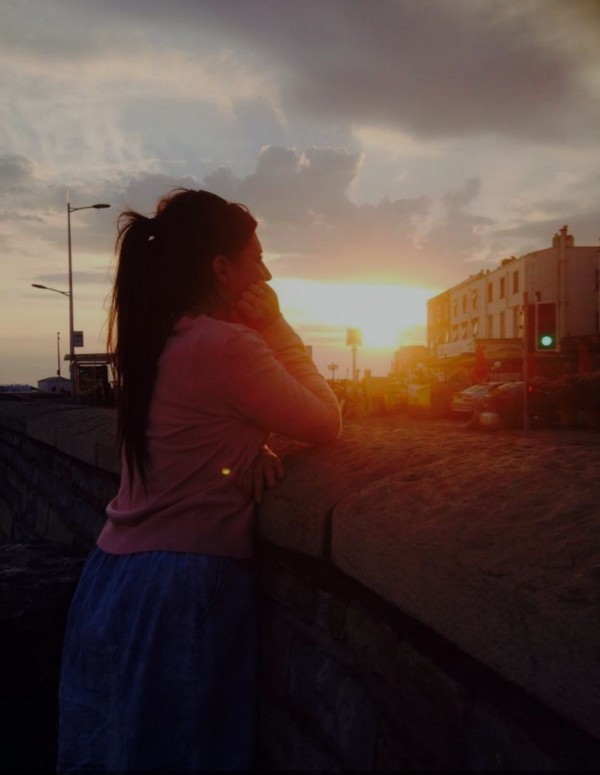 Woman watching sunset over city street.