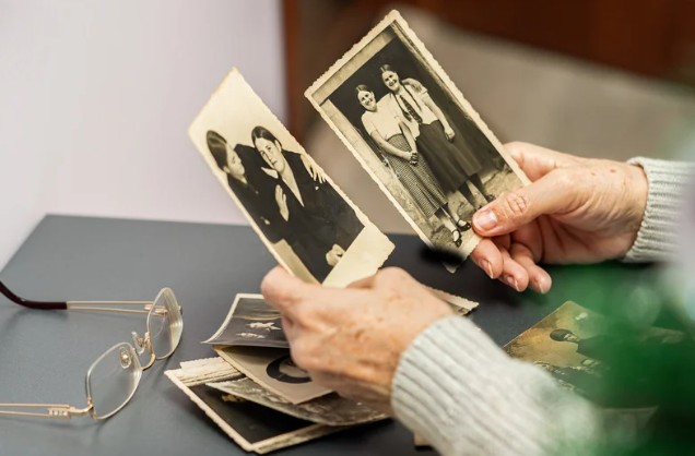 Person holding vintage black and white photographs.
